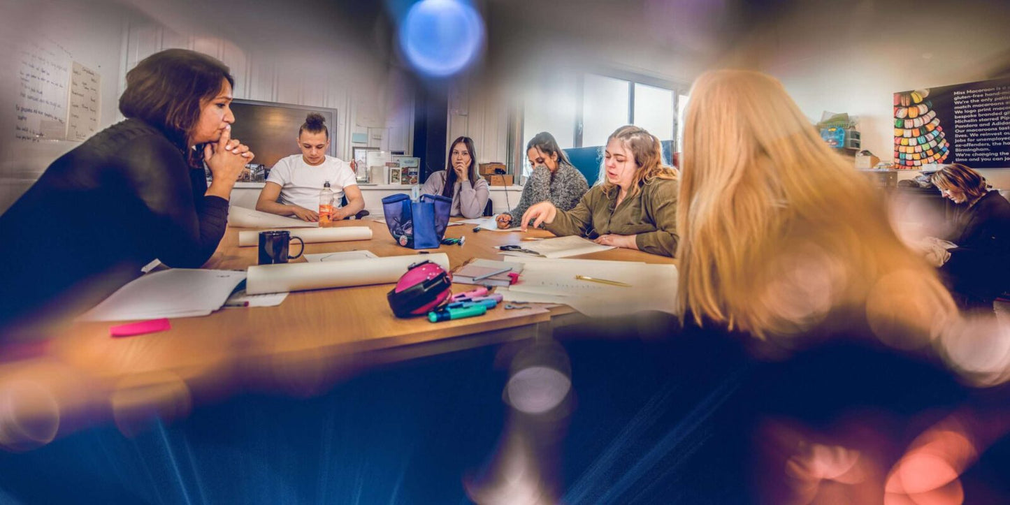 Miss Macaroon MacsMAD trainees sit around an office table completing a group session with the Psychotherapist and counsellor.