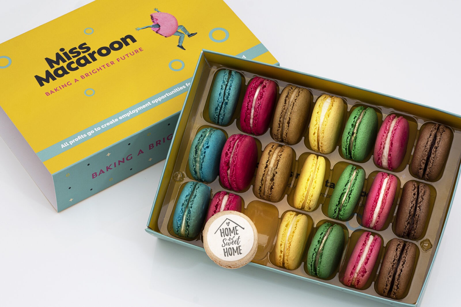 Gift box of 21 macaroons. Three of each flavour, seven different bright coloured macaroons, with one cream macaroons printed with decorate words 'Home Sweet Home'.