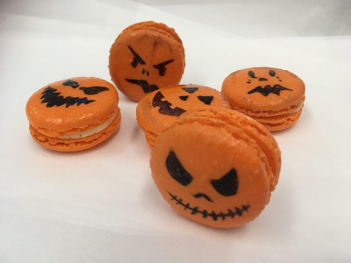 Five Halloween Jack O' Lantern decorated macaroons looking at you