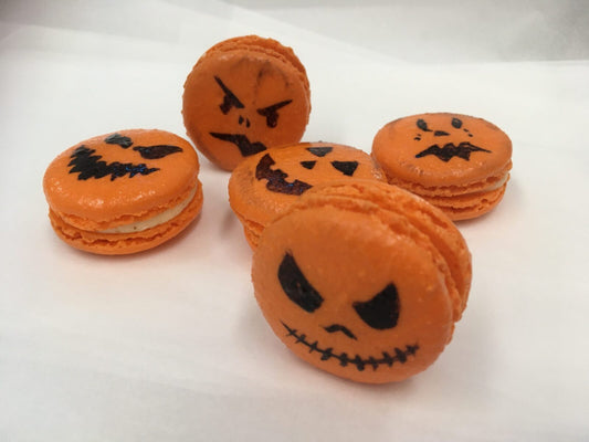 Five Halloween Jack O' Lantern decorated macaroons looking at you