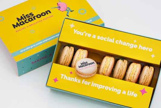 Yellow gift box of seven cream macaroons printed with a company logo.