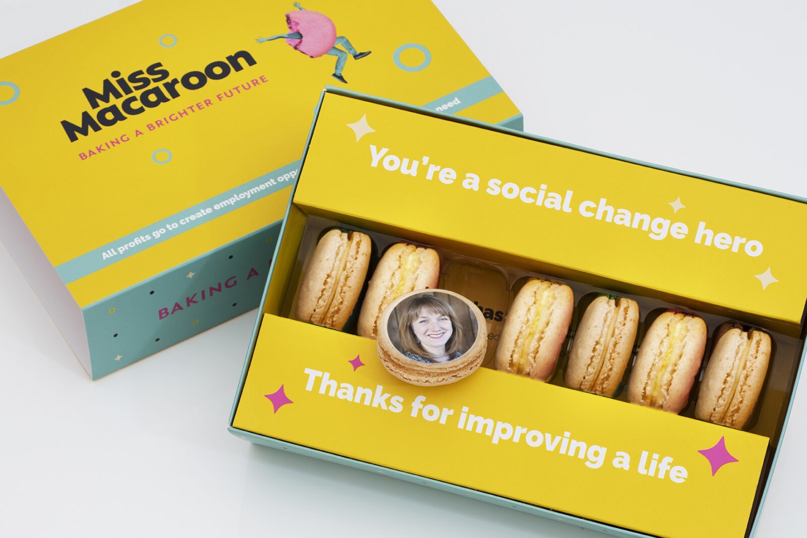 Yellow gift box of seven cream macaroons printed with a woman's face.