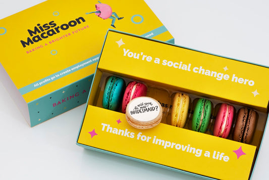 Gift box of seven macaroons. One of each flavour, seven different bright coloured macaroons, with "Will you be my Bridesmaid?" picture printed on.